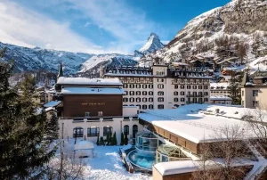 Vue extérieure sur la façade majestueuse du Mont Cervin Palace en hiver avec le mont Cervin enneigé en arrière-plan.