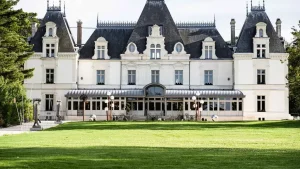 Façade néoclassique en tuffeau clair du Château de Maubreuil et sa véranda abritant le restaurant, vue depuis la pelouse du parc.