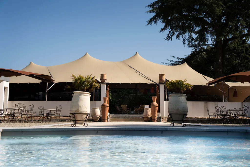 Le Salon Nomade, restaurant d'été sous tente près de la piscine du Château de Maubreuil, jarres en terre cuite et mobilier en fer forgé.