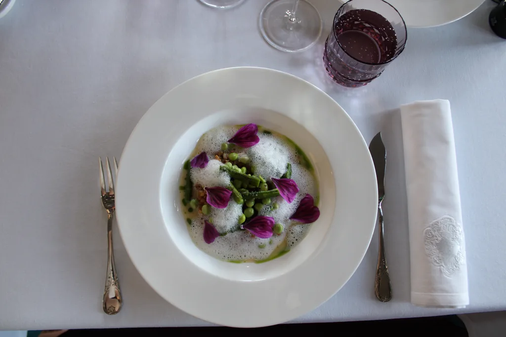 Assiette de La Table du Marquis, restaurant du Château de Maubreuil sélectionné au guide Michelin 2025 : légumes du potager, petits pois et fleurs comestibles.