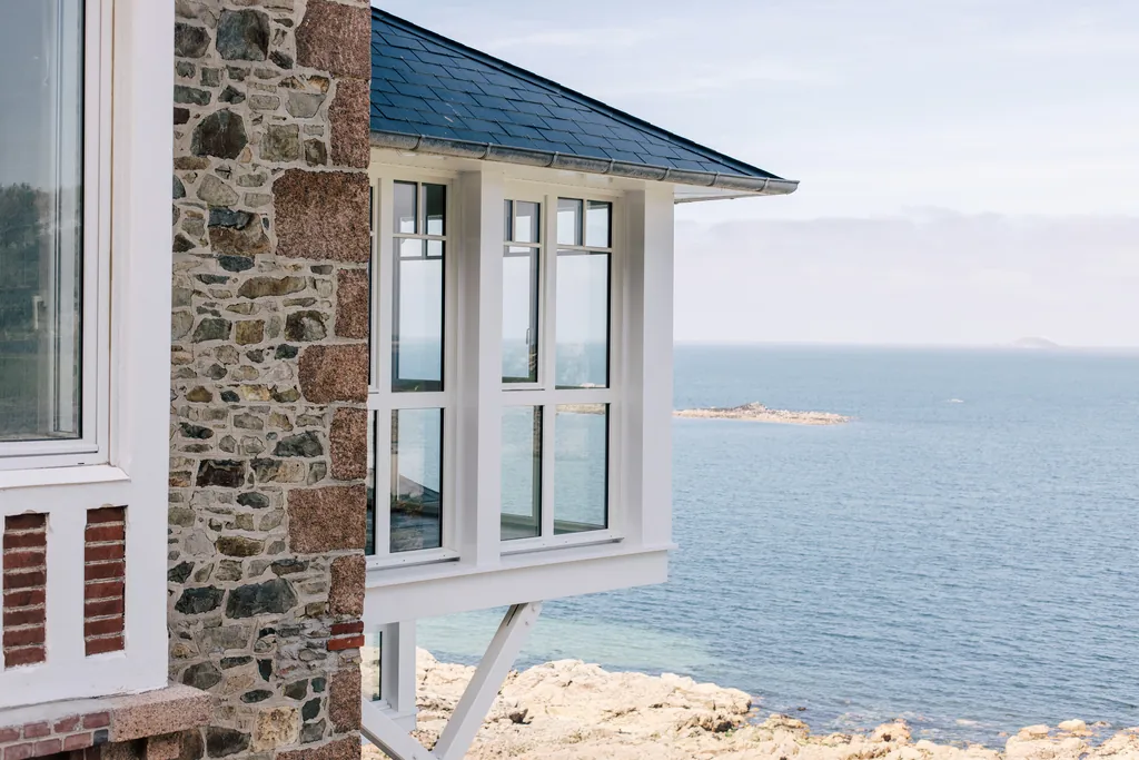 Le bow-window d'angle de l'hôtel Les Bassans, pierre et brique sous un toit d'ardoise, en surplomb de la mer à Perros-Guirec.