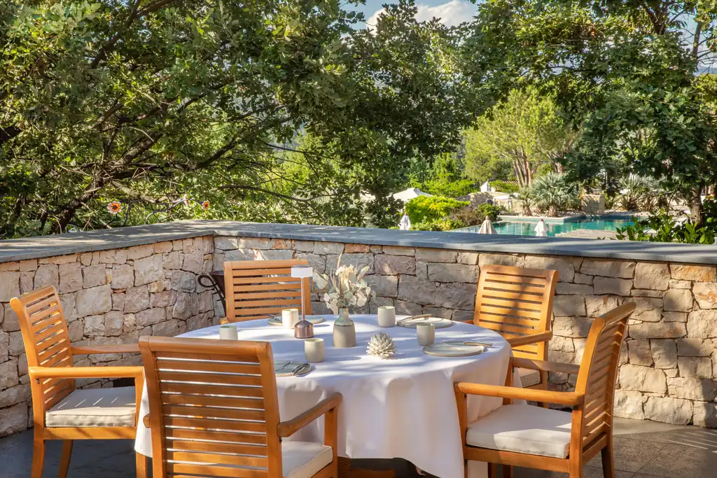 Table dressée sur une terrasse de restaurant à Terre Blanche, vue sur la piscine et les jardins