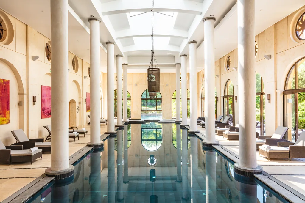 Piscine intérieure du spa de Terre Blanche, longue nef bordée de colonnes et de baies cintrées