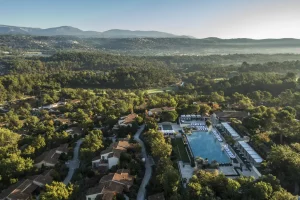 Vue aérienne du domaine de Terre Blanche, villas dans la pinède et piscine centrale face aux collines varoises