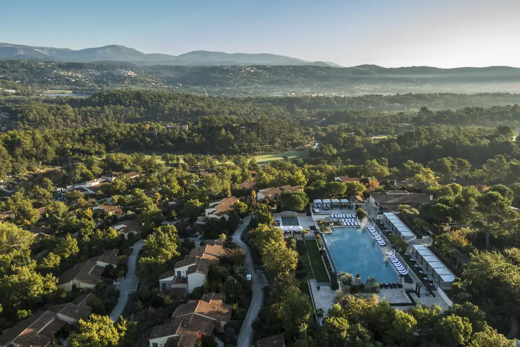 Vue aérienne du domaine de Terre Blanche, villas dans la pinède et piscine centrale face aux collines varoises