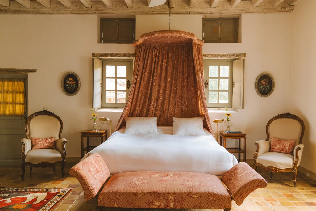Chambre à baldaquin de toile de Jouy rouge au Logis des Grives, Les Prés d'Eugénie, fauteuils Louis-Philippe et sol en tomettes.