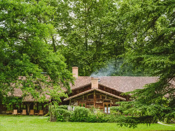 La Ferme Thermale des Prés d'Eugénie, bâtisse landaise aux toits de tuiles nichée dans les bois du domaine.