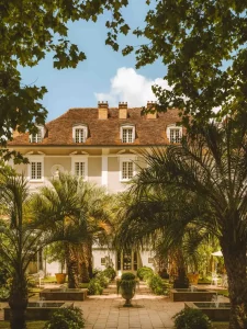 La Grande Maison des Prés d'Eugénie, façade d'allure coloniale et carré de palmiers autour d'une cour à fontaines.