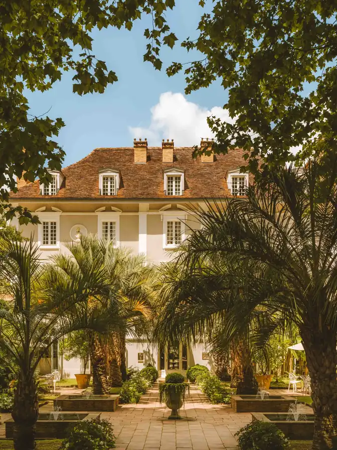 La Grande Maison des Prés d'Eugénie, façade d'allure coloniale et carré de palmiers autour d'une cour à fontaines.