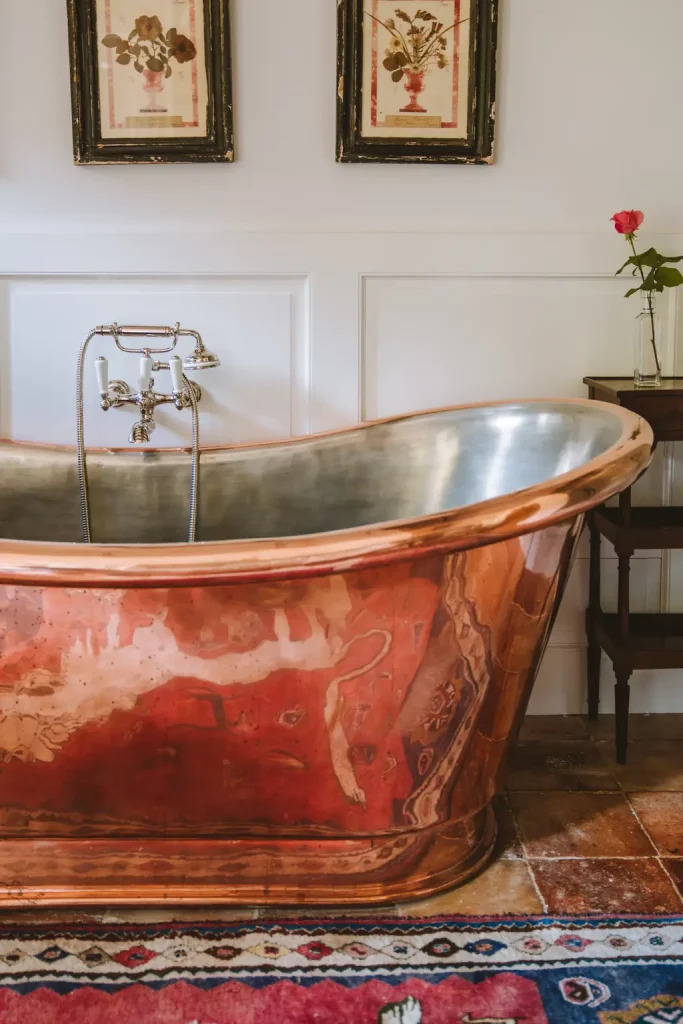 Salle de bain d'une chambre des Prés d'Eugénie, baignoire en cuivre étamé et estampes de fleurs séchées.