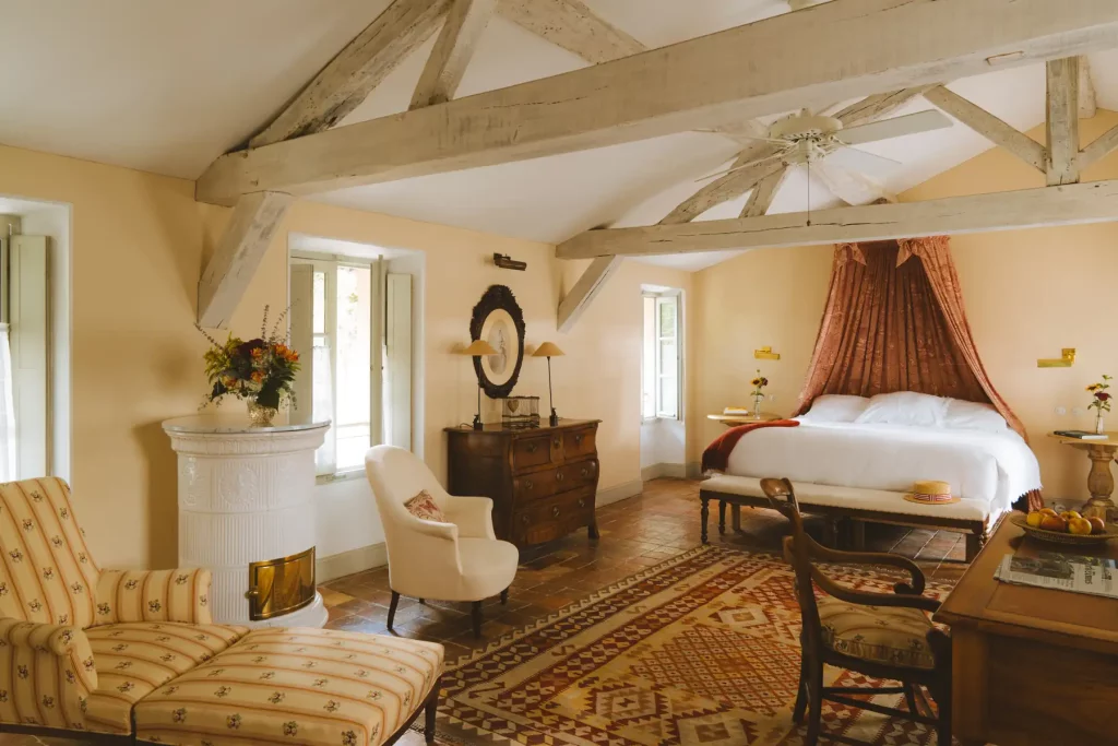Vaste suite du Logis des Prés d'Eugénie, poêle en faïence blanche, lit à baldaquin et charpente apparente.