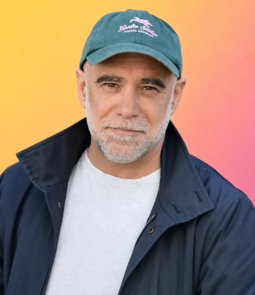 Portrait d'Arnaud Chaigneau, cofondateur de Kastel, en buste, casquette verte et veste bleu marine sur un fond dégradé jaune et rose.