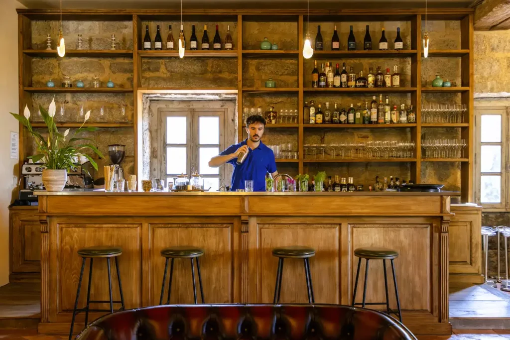 Le bar du Hameau de Saparale, son comptoir en bois et ses étagères de bouteilles.