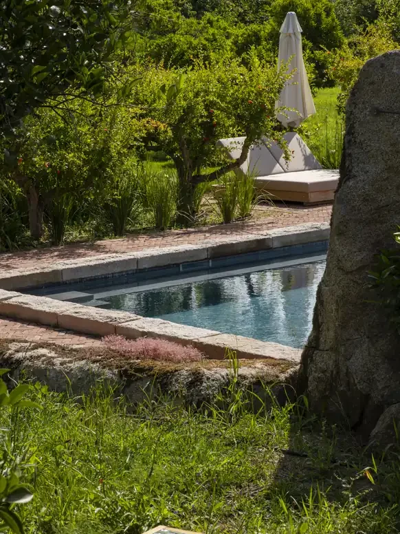 Piscine en pierre entourée de verdure et de grenadiers au Hameau de Saparale.