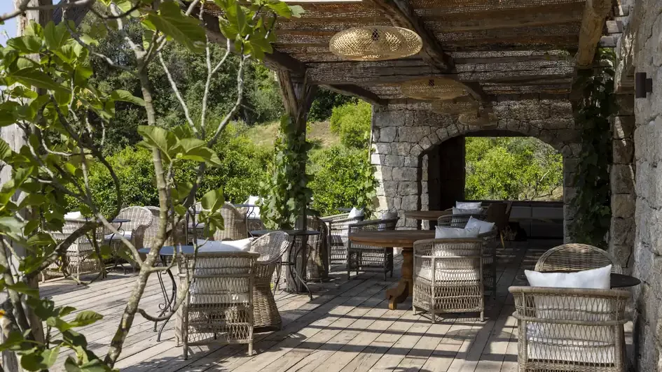 Terrasse sous tonnelle, fauteuils en rotin et vue sur le maquis au Hameau de Saparale.