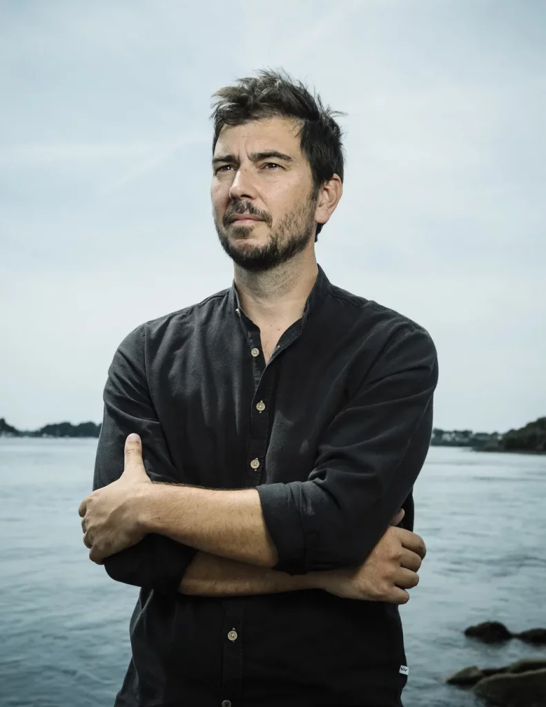 Maxime Blondeau, cosmographe, debout les bras croisés au bord de l'eau à Vannes.