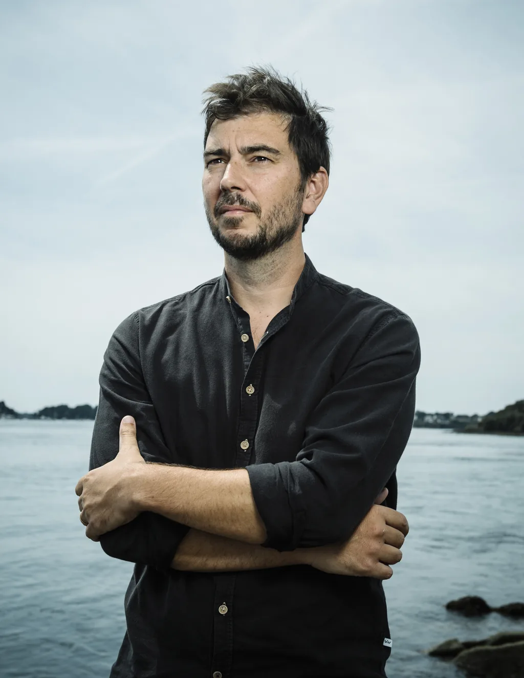 Maxime Blondeau, cosmographe, debout les bras croisés au bord de l'eau à Vannes.
